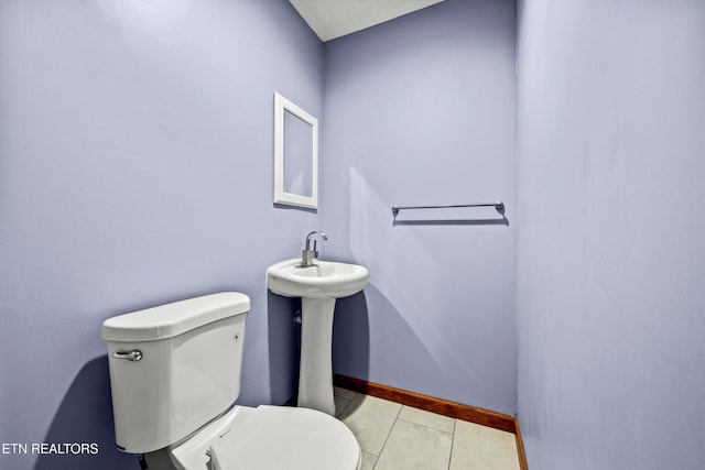 bathroom with baseboards, tile patterned flooring, and toilet