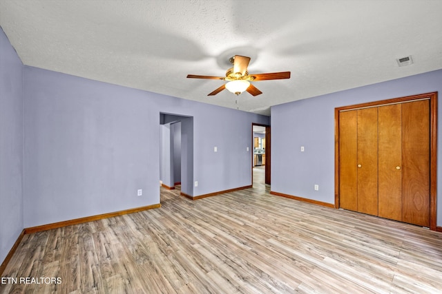 unfurnished bedroom featuring light wood-type flooring, baseboards, and a closet