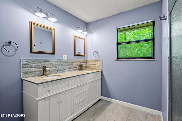 bathroom featuring tile patterned flooring, double vanity, baseboards, tasteful backsplash, and a sink