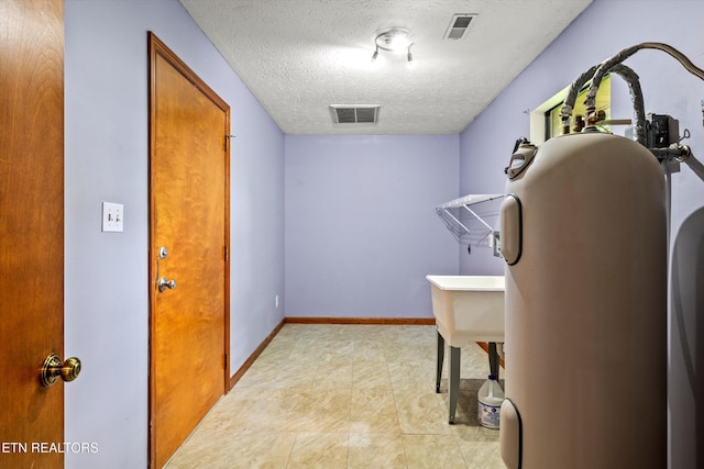 laundry room featuring baseboards, a textured ceiling, and visible vents