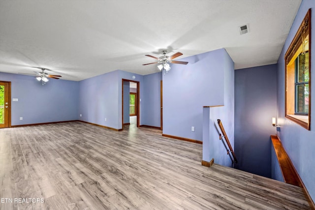 unfurnished living room featuring visible vents, baseboards, ceiling fan, and wood finished floors