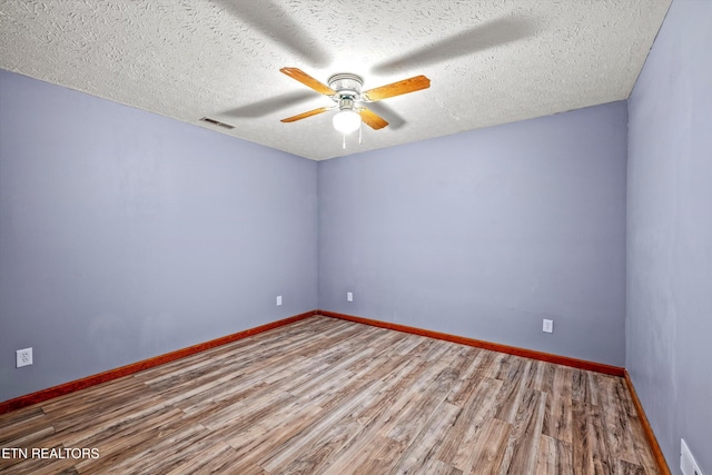 unfurnished room with baseboards, a ceiling fan, wood finished floors, and visible vents