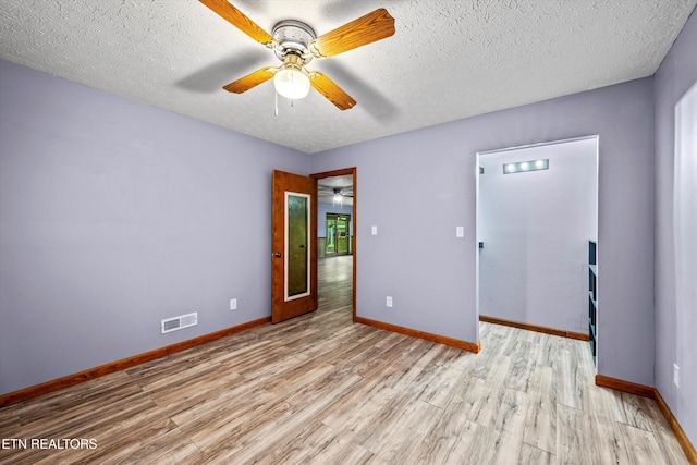spare room featuring a ceiling fan, baseboards, visible vents, and light wood finished floors