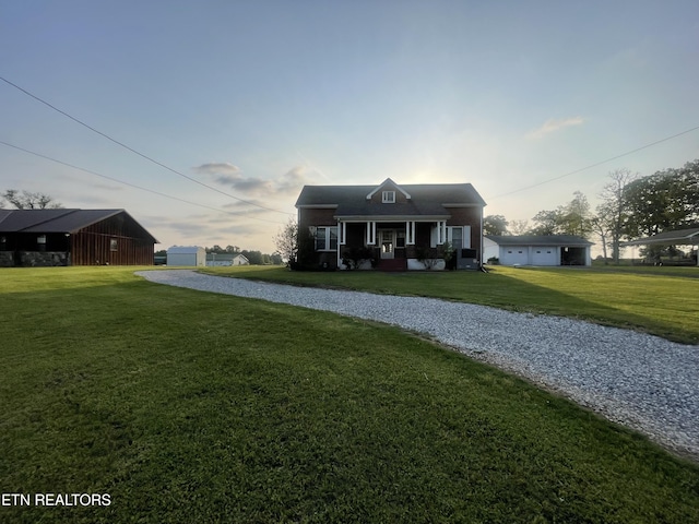 bungalow-style house featuring a detached garage, covered porch, driveway, and a front yard