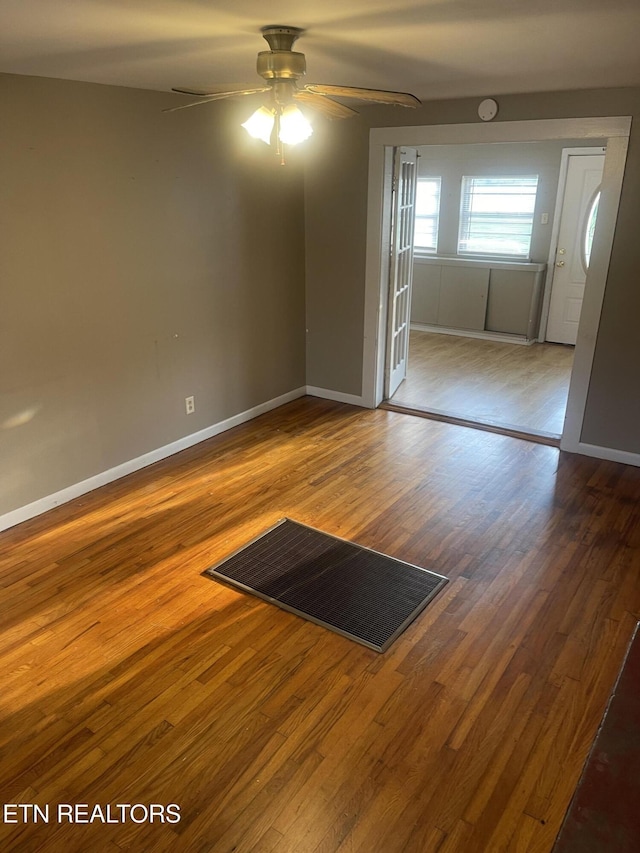 unfurnished room with a ceiling fan, baseboards, visible vents, and wood finished floors