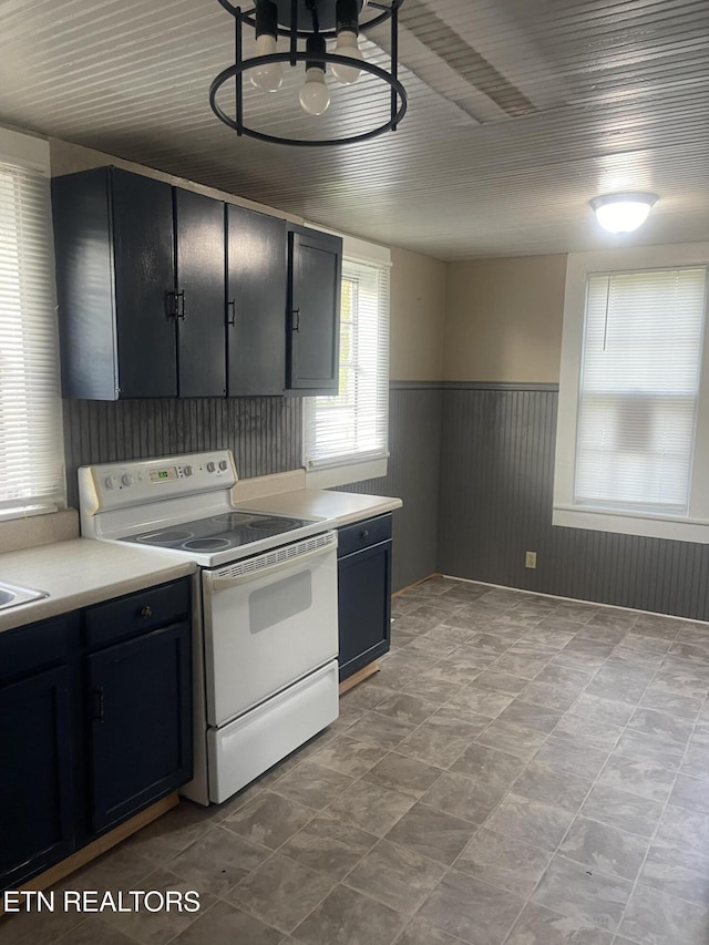 kitchen with white electric stove, wainscoting, a sink, light countertops, and dark cabinets