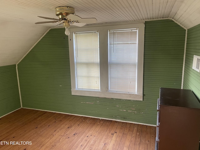 bonus room featuring wooden walls, ceiling fan, vaulted ceiling, and hardwood / wood-style flooring