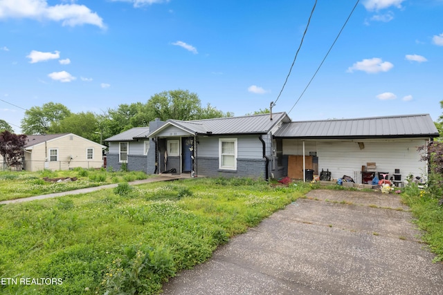 ranch-style house featuring fence, metal roof, and brick siding