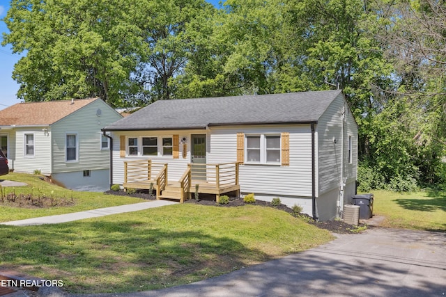 view of front of house with roof with shingles and a front yard