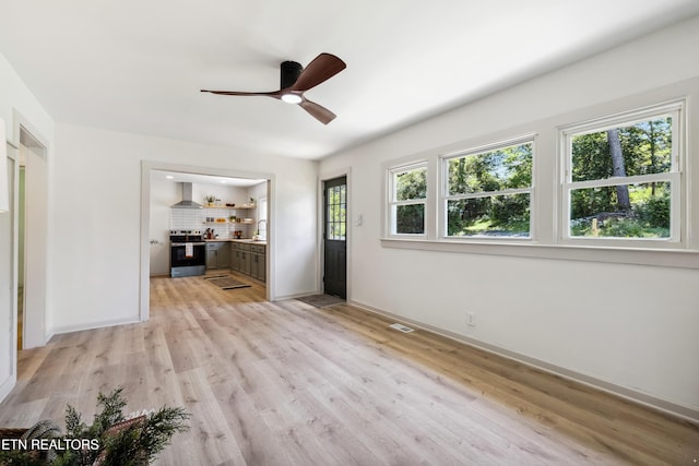 unfurnished living room featuring baseboards, light wood-style flooring, visible vents, and a ceiling fan