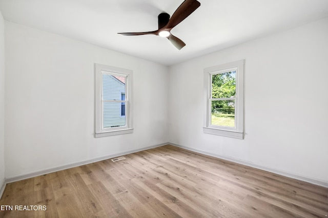 spare room with light wood-style floors, visible vents, baseboards, and ceiling fan