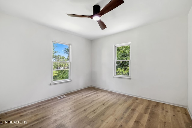 empty room with a healthy amount of sunlight, ceiling fan, light wood-type flooring, and visible vents