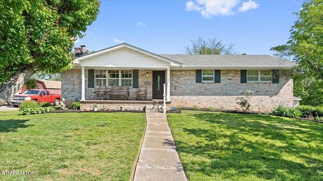 view of front facade featuring covered porch, brick siding, crawl space, and a front yard
