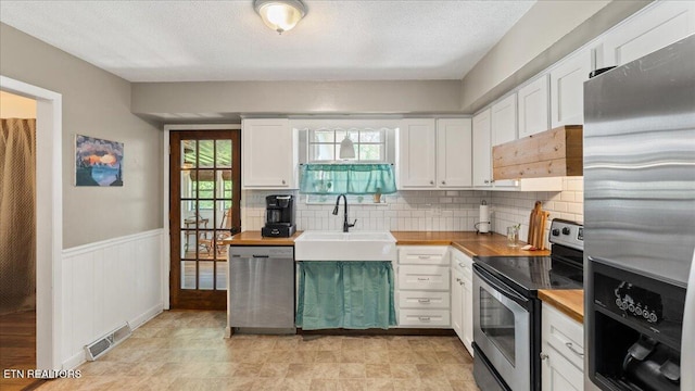 kitchen with a sink, appliances with stainless steel finishes, custom range hood, and wood counters