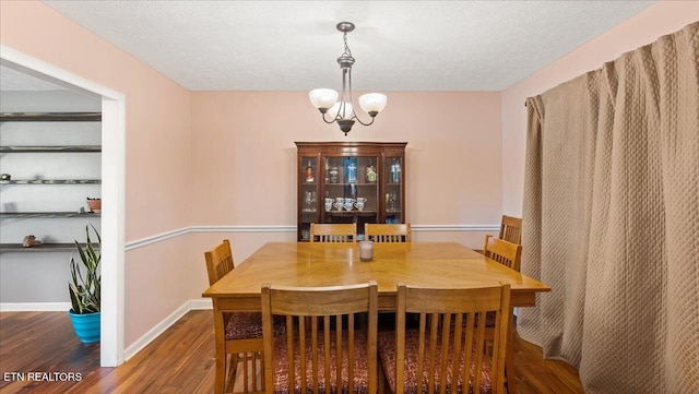 dining room featuring a textured ceiling, baseboards, and wood finished floors