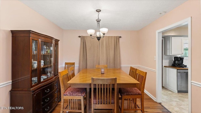 dining area featuring an inviting chandelier, a textured ceiling, and wood finished floors