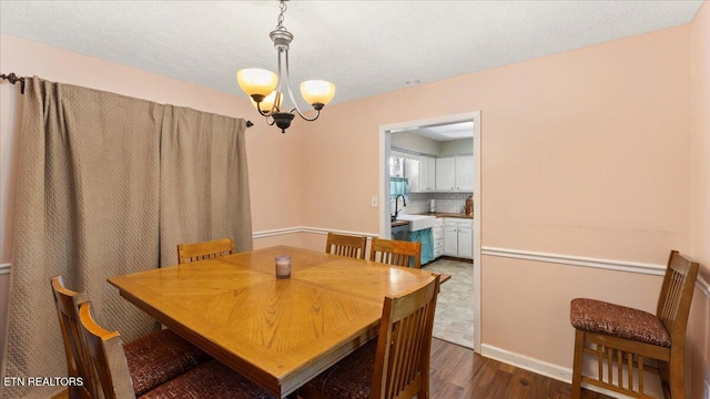 dining space featuring an inviting chandelier, baseboards, and dark wood finished floors