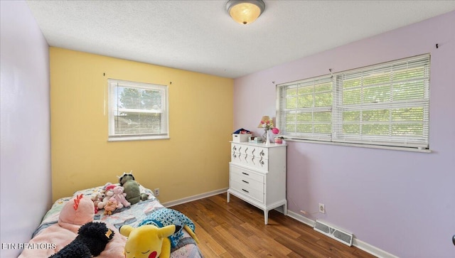bedroom featuring baseboards, multiple windows, wood finished floors, and visible vents
