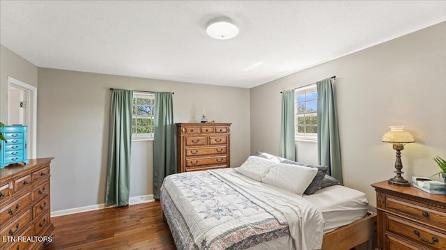 bedroom with baseboards, multiple windows, and dark wood-type flooring