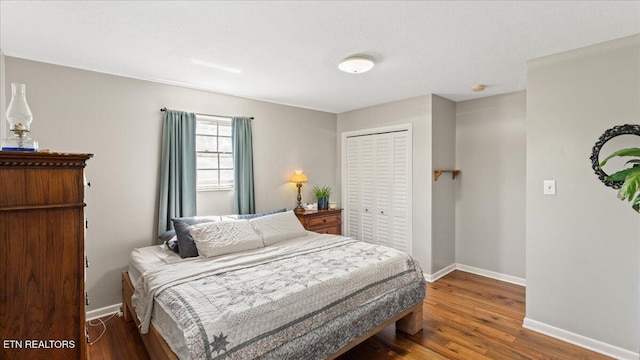 bedroom with baseboards, wood finished floors, and a closet