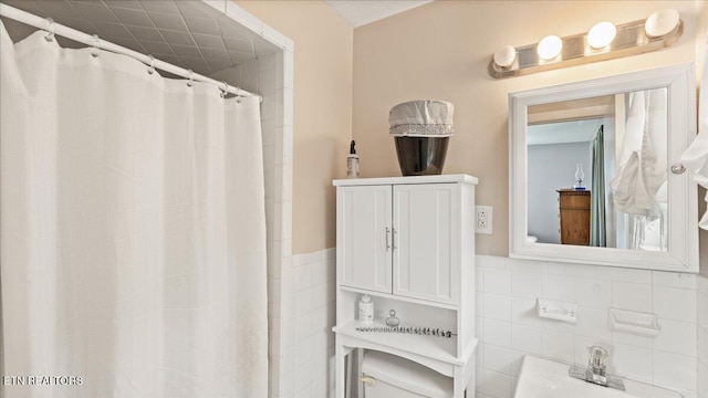 bathroom featuring tile walls, wainscoting, and curtained shower