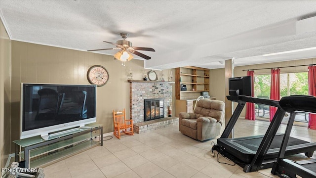 workout area with a fireplace, baseboards, a textured ceiling, tile patterned floors, and a ceiling fan