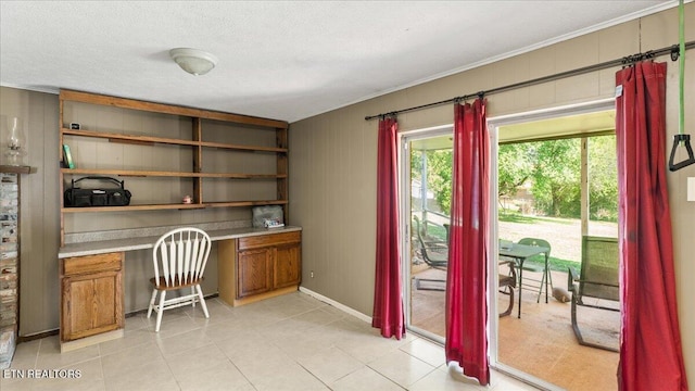home office with a textured ceiling, built in study area, light tile patterned floors, baseboards, and ornamental molding