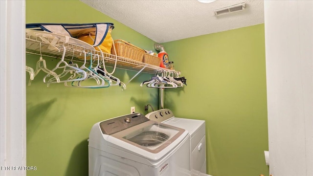 laundry room with laundry area, a textured ceiling, washing machine and dryer, and visible vents