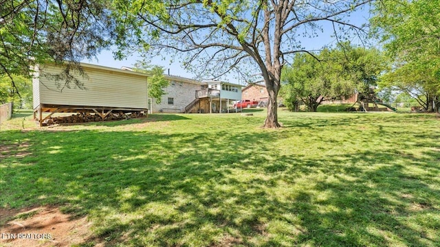 view of yard featuring a playground, fence, stairway, and a deck