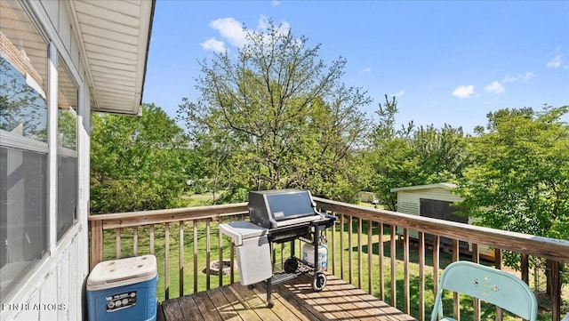 wooden deck with a storage unit, an outdoor structure, a yard, and area for grilling