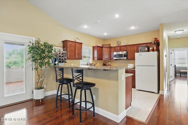 12116 W Kings Gate Rd, Farragut, TN 37934 - kitchen featuring freestanding refrigerator, stainless steel microwave, a peninsula, a breakfast bar, and wood finished floors