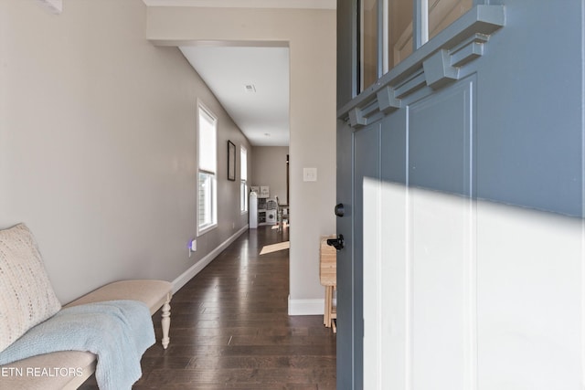 corridor featuring dark wood-type flooring and baseboards