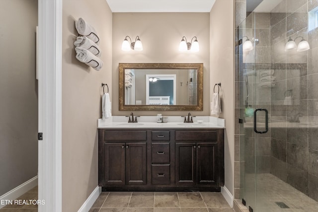 bathroom with a shower stall, baseboards, double vanity, and tile patterned floors