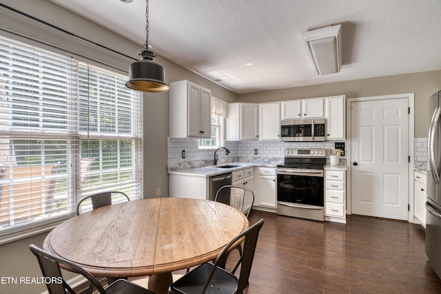 kitchen with decorative backsplash, light countertops, white cabinetry, a sink, and stainless steel appliances