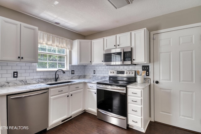 kitchen with stainless steel appliances, white cabinetry, a sink, and tasteful backsplash