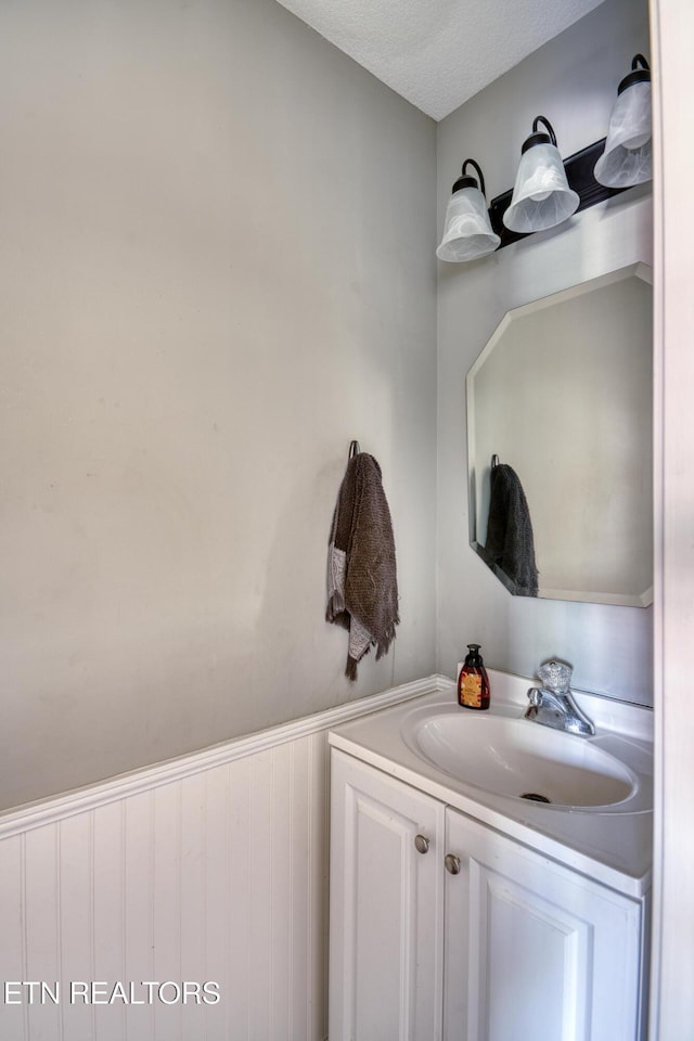 bathroom with vanity and a wainscoted wall