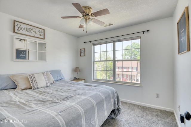 bedroom featuring visible vents, carpet floors, baseboards, ceiling fan, and a textured ceiling