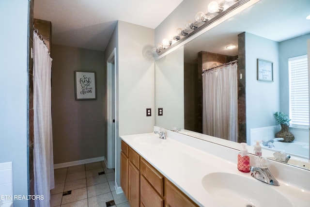 bathroom featuring double vanity, baseboards, a sink, and tile patterned flooring
