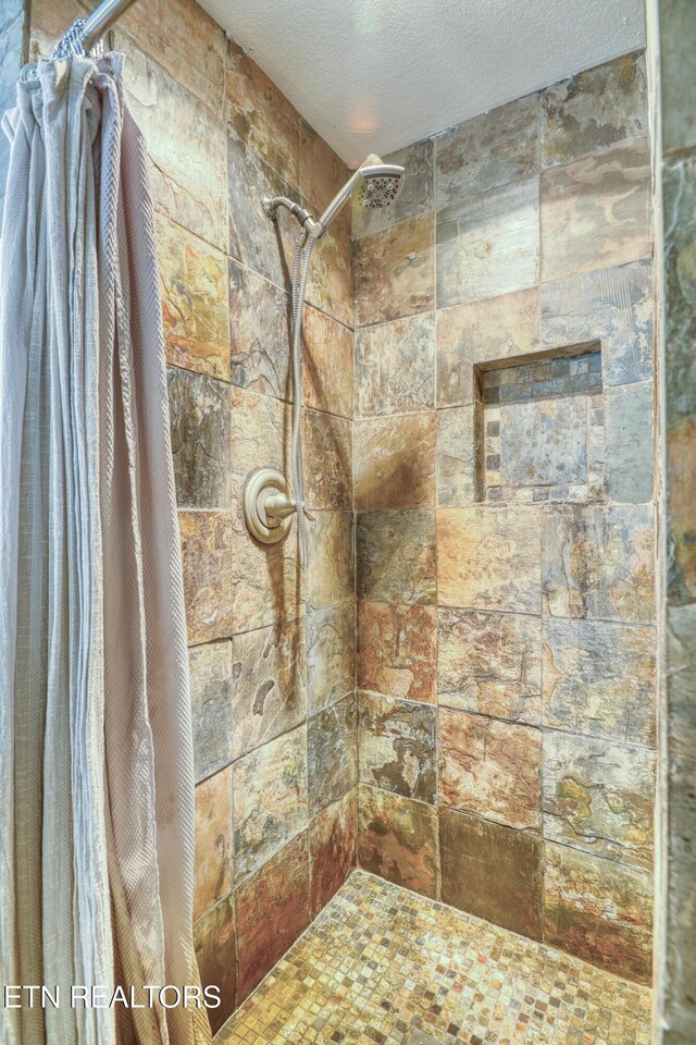 bathroom featuring a textured ceiling and tiled shower