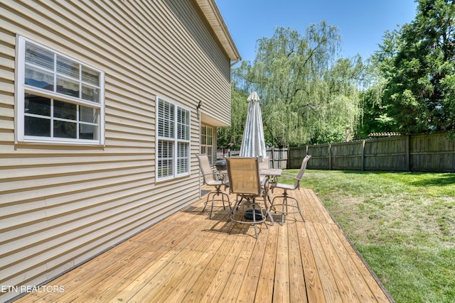 deck with a fenced backyard, outdoor dining area, and a yard