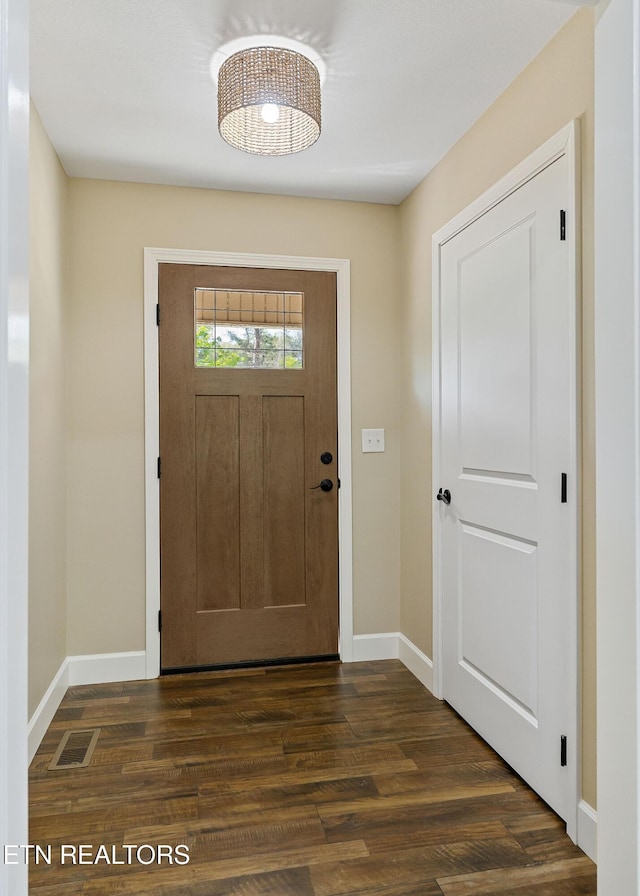 foyer entrance featuring baseboards, visible vents, and dark wood-style floors
