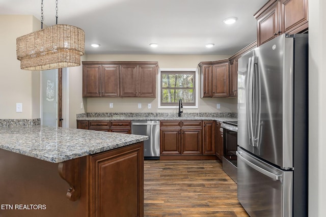 kitchen featuring dark wood-style flooring, a peninsula, a kitchen breakfast bar, a sink, and stainless steel appliances