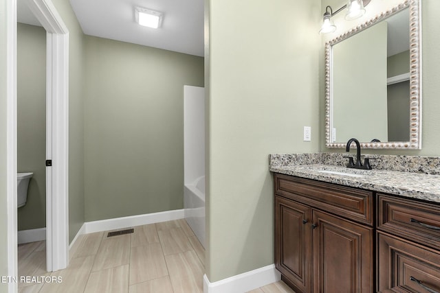 bathroom featuring a washtub, visible vents, vanity, baseboards, and toilet