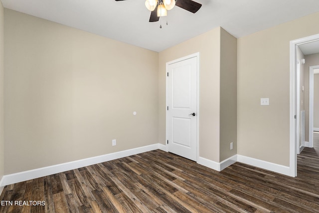 unfurnished room with baseboards, a ceiling fan, and dark wood-style flooring