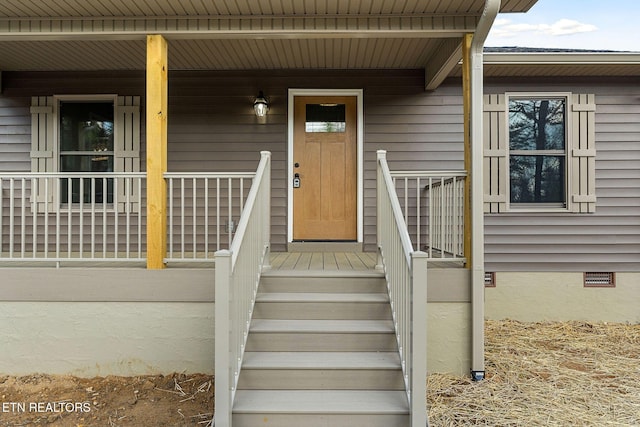 view of exterior entry featuring covered porch and crawl space