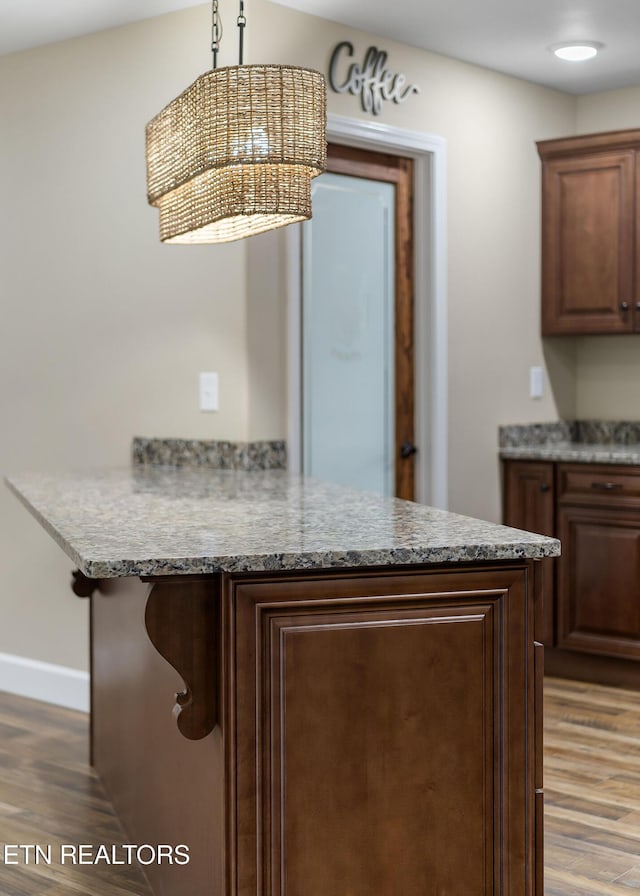 kitchen featuring pendant lighting, baseboards, a peninsula, and wood finished floors