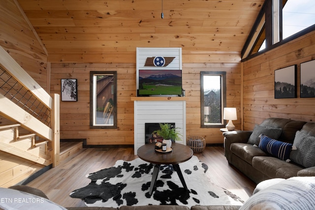 living room featuring stairs, wood walls, wood ceiling, and lofted ceiling