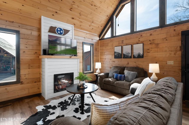 living room featuring wooden walls, visible vents, wooden ceiling, wood finished floors, and vaulted ceiling