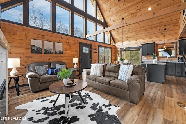 living area with wooden walls, high vaulted ceiling, and light wood finished floors