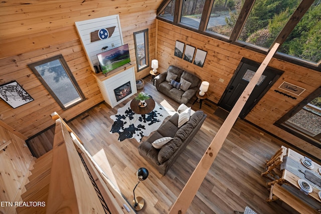 living room featuring wooden walls, a glass covered fireplace, and wood finished floors